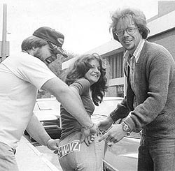 Paul Mayer assists a WAVZ listener with her bumper sticker as John Walker observes